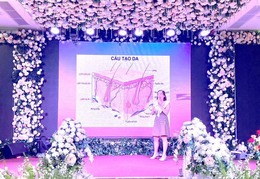 A person standing on a stage with flowers around her

Description automatically generated