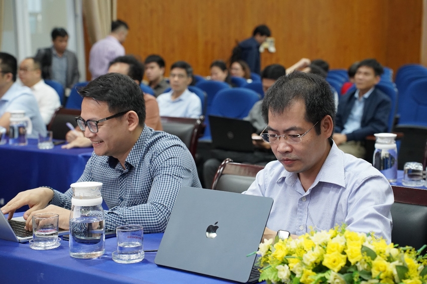 Men sitting at a table with laptops and flowers

Description automatically generated