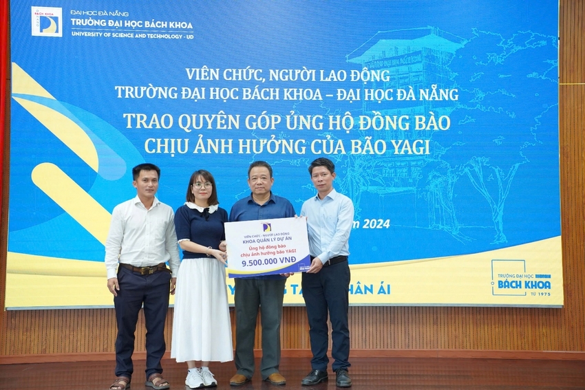 A group of people standing on a stage holding a sign
Description automatically generated