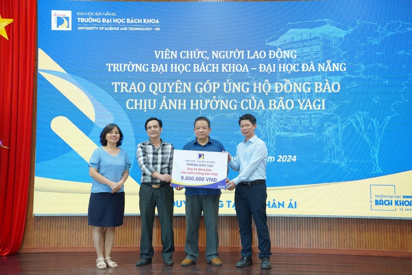 A group of people standing in front of a large banner

Description automatically generated