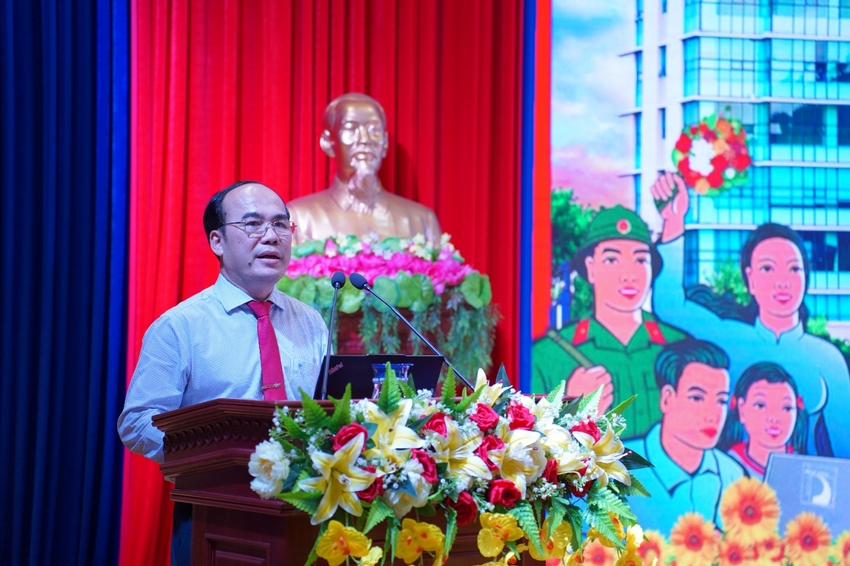 A person standing at a podium with flowers and a statue behind him

Description automatically generated
