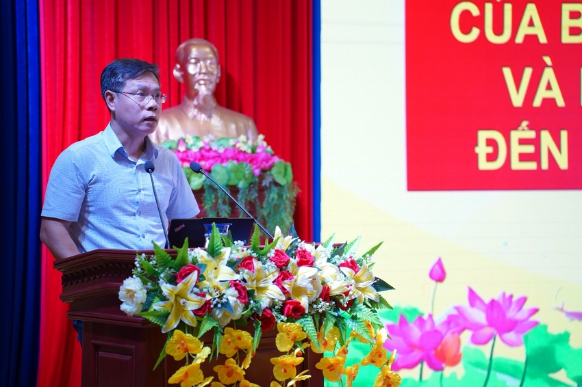 A person standing at a podium with a microphone and flowers
Description automatically generated