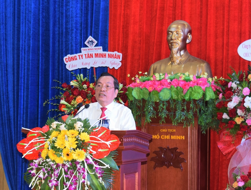 A person standing behind a podium with flowers and a statue behind him

Description automatically generated with low confidence