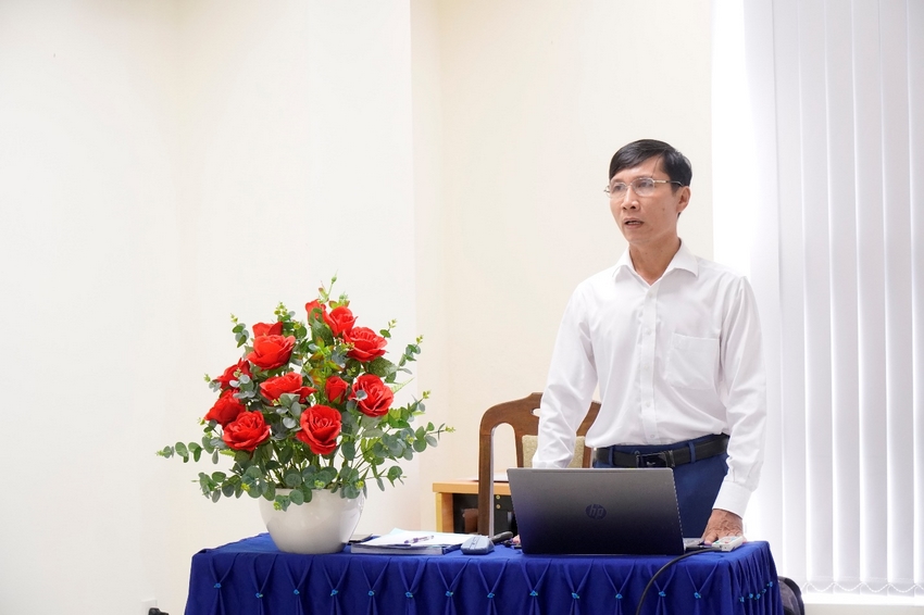 A person standing behind a table with a computer and a bouquet of flowers

Description automatically generated