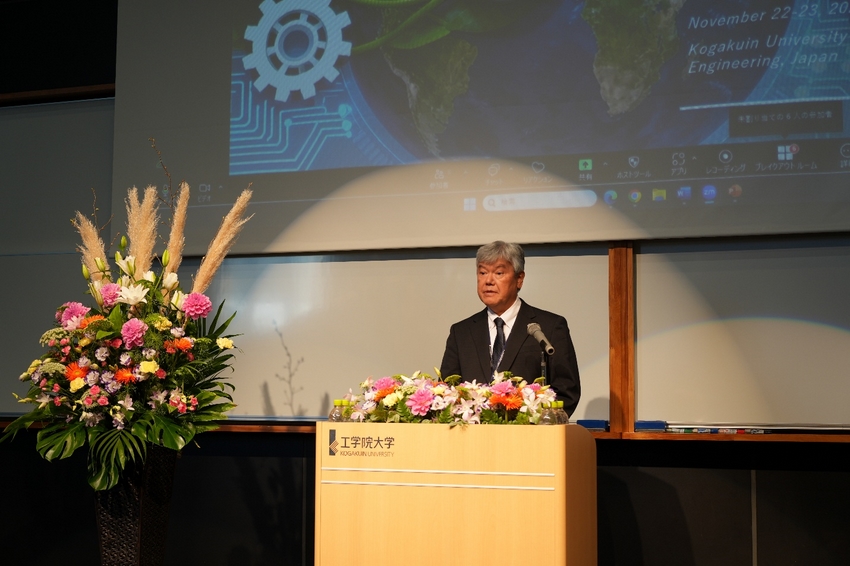 A person standing at a podium with flowers and a projector screen

AI-generated content may be incorrect.