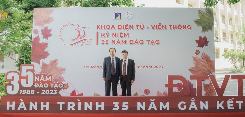Two men standing in front of a sign

Description automatically generated