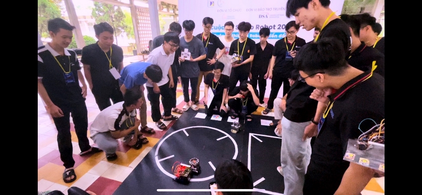 A group of people standing around a black circle with a robot

Description automatically generated