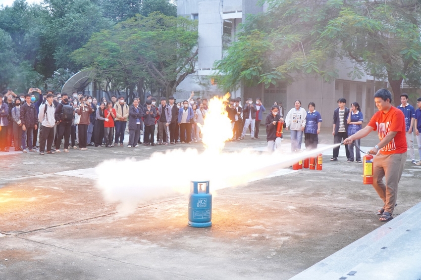 A group of people watching a fire extinguisher

Description automatically generated