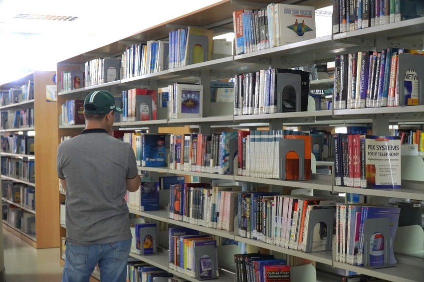 A person looking at books on shelves
Description automatically generated
