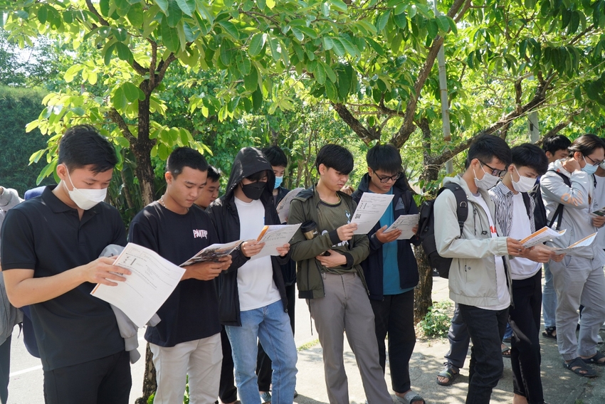 A group of people standing outside reading papers

Description automatically generated with low confidence
