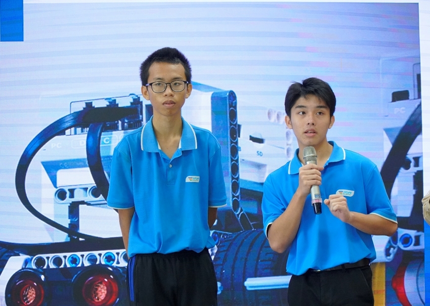 A group of young men in blue shirts holding microphones

Description automatically generated