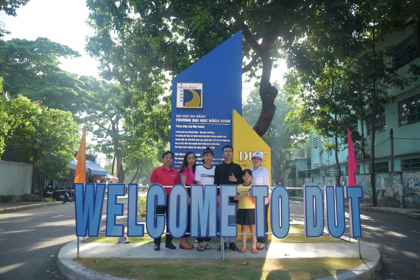 A group of people standing under a sign

Description automatically generated